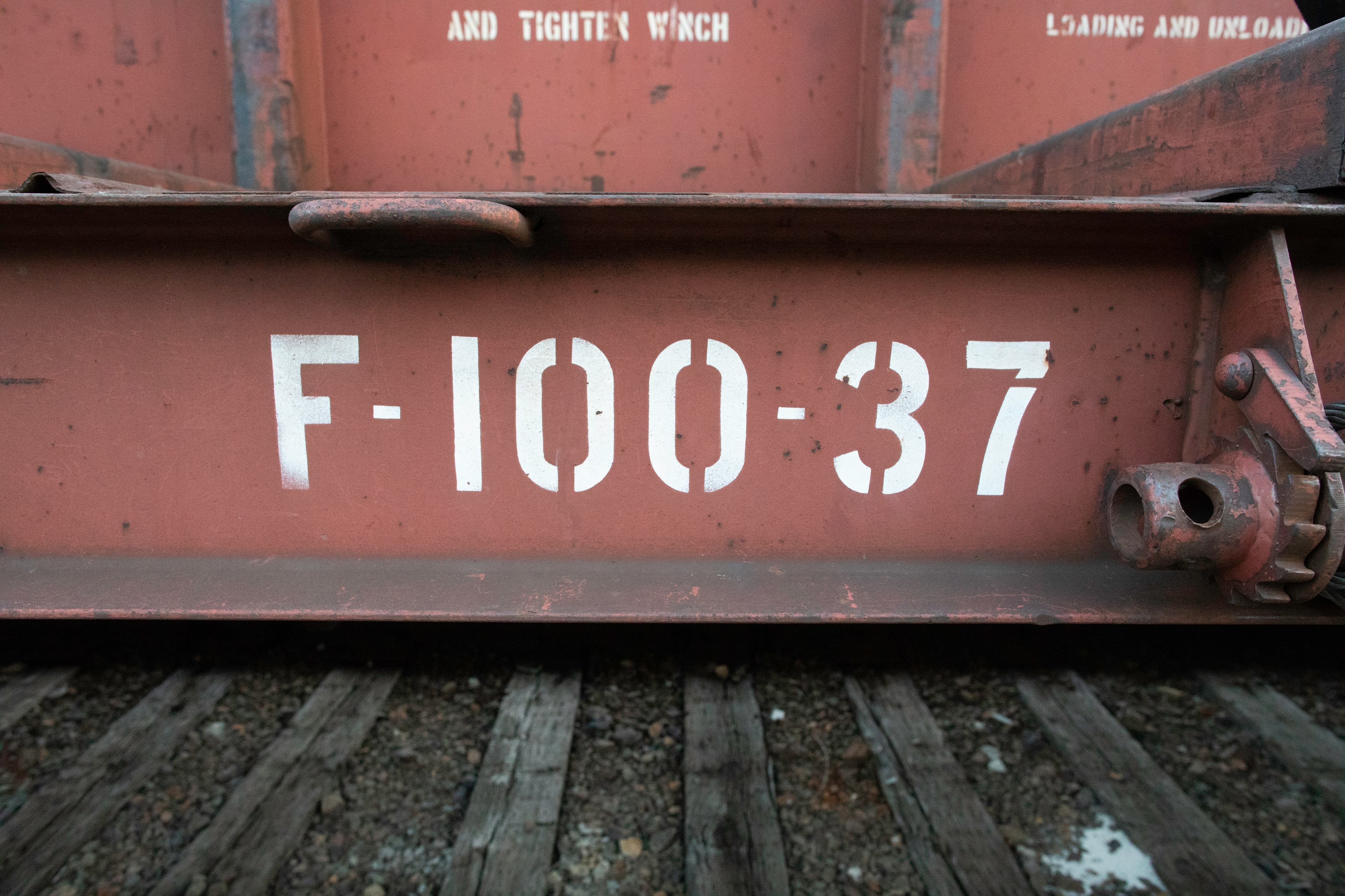 F-100-37 stencil and latch hardware on an industrial rail-car beam
